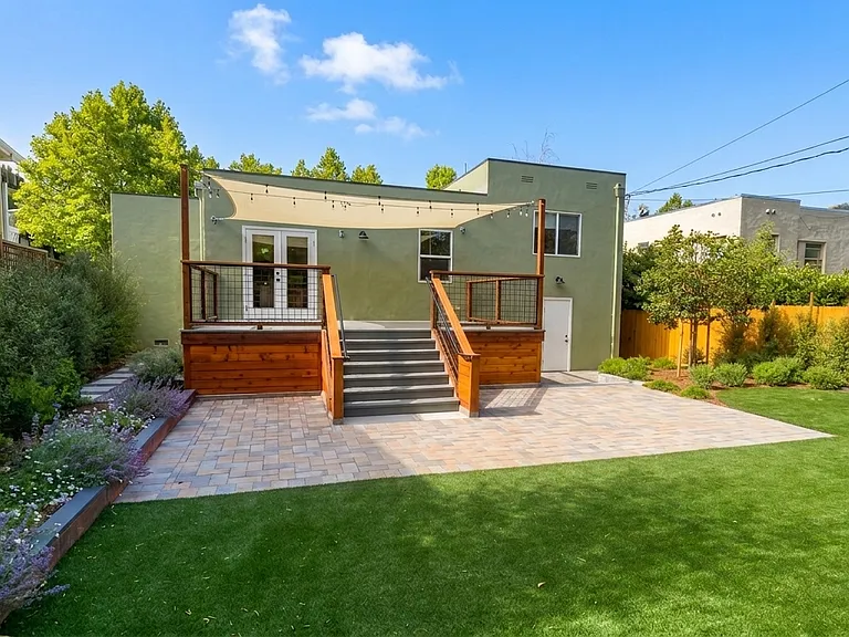 Backyard with a deck off the dining room, sunshade, and bistro lighting. Backyard permeable pavers, new turf and landscaping
