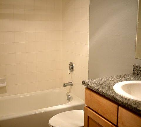 Tiled shower/bath and granite countertop in the bathroom.