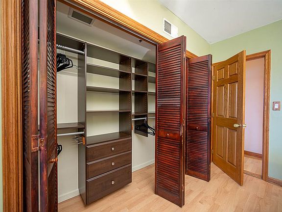 Large closet with built-in shelving, hanging rods, drawers, and folding wooden doors.