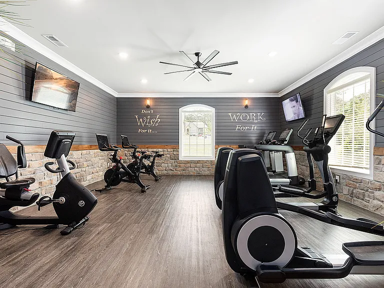 Modern fitness room with sleek exercise bikes, motivational quotes on walls, and ample natural light.