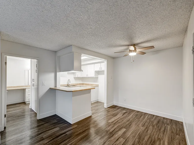 an empty dining room with a kitchen and a ceiling fan