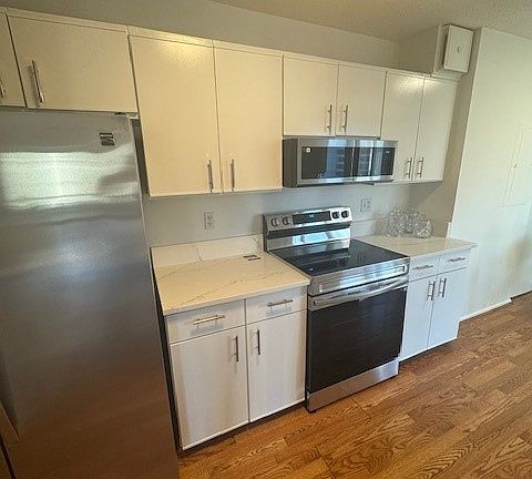 New Renovated Kitchen with new stove, microwave, stainless steel refrigerator and hardwood floors.