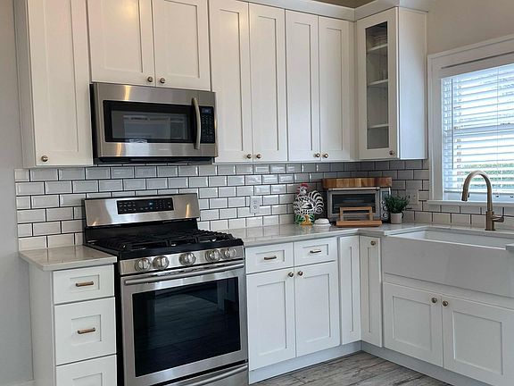 Bright kitchen with gas range, farmhouse sink, newer dishwasher, newer refridgerator