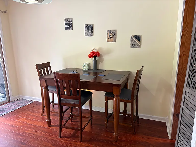 Dining area with a pub-height table for four, set on hardwood floors and positioned near a sliding door for easy access.