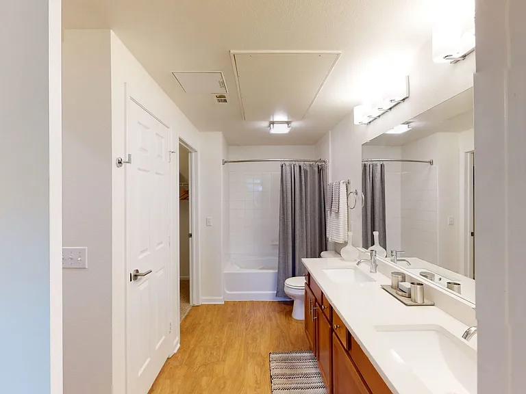 Apartment bathroom with large soaking tub, wood-style flooring and double sinks.