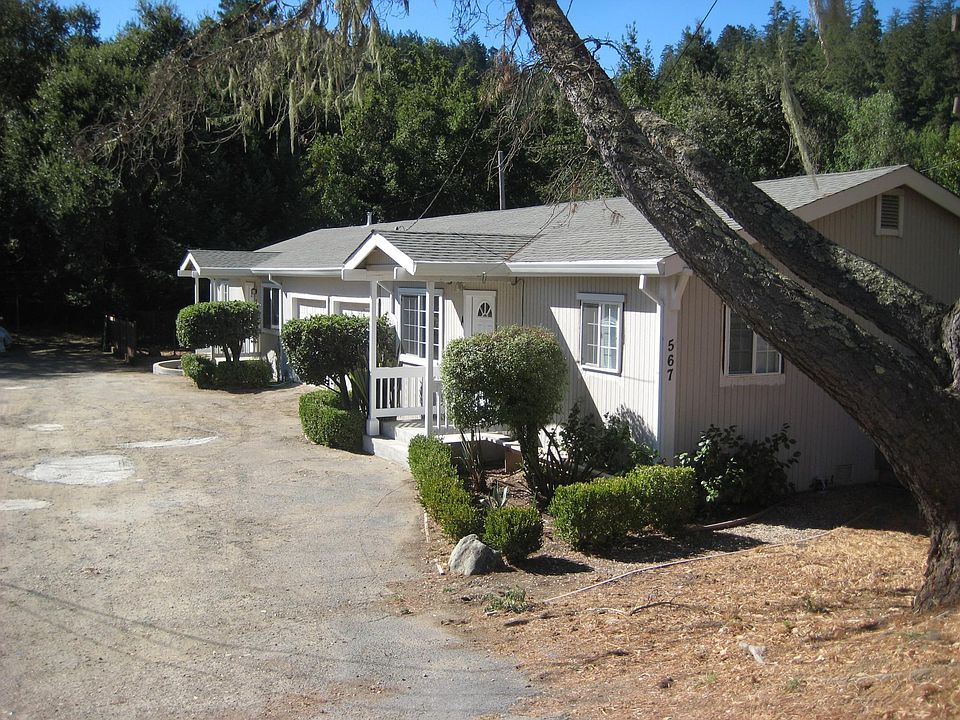 Front porches of duplex. Garages are in between. Forested backdrop behind.