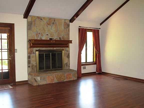 Spacious and cozy living room with vaulted ceilings, wood beams and stone fireplace