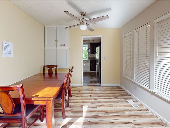 Ceiling fan and laminate wood flooring in the dining area.>