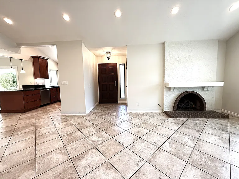 Living room with fireplace, front door and kitchen to the left.