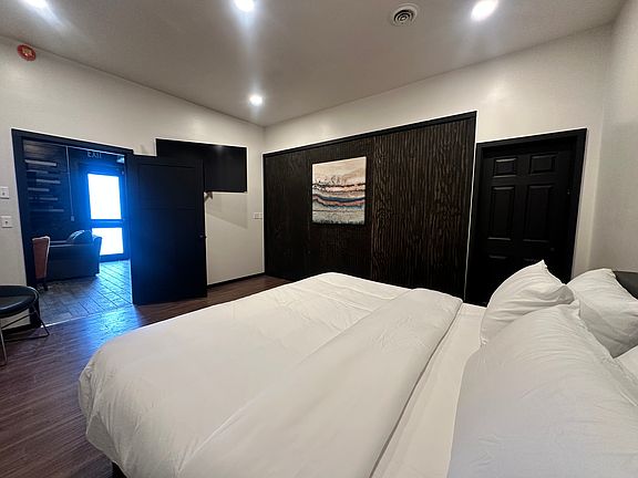 Spacious Master Bedroom with rich textured art work and stylish wood accent wall, with 55" TV, walk-in closet- get a cozy night sleep in a Kingsize bed.
