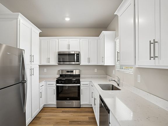 The kitchen has stainless steel appliances and plank flooring.
