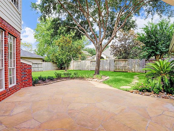 Lovely extended flagstone patio bordered with tropical landscaping and spacious yard. Great for enjoying the outdoors year around. The garage also offers a 15 ft extension with extra fridge.