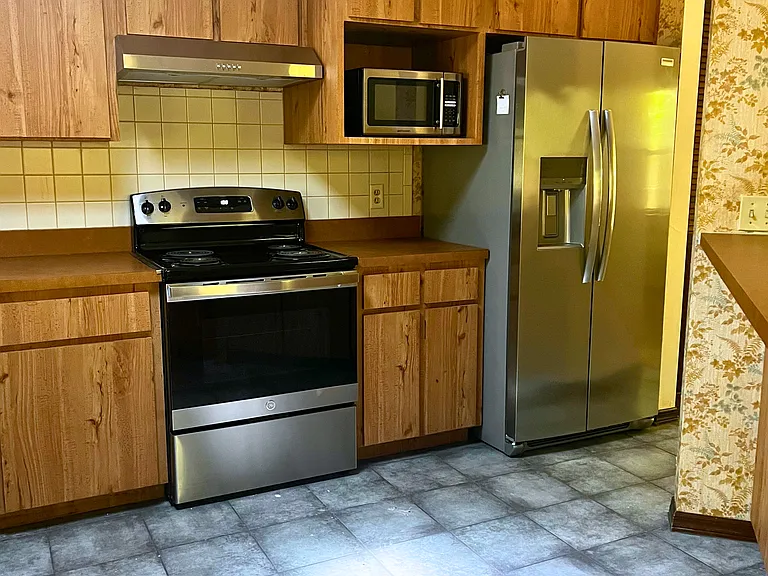 Kitchen has tile floor and includes microwave, new range hood (2026), fridge (2024), and oven/range (2017)
