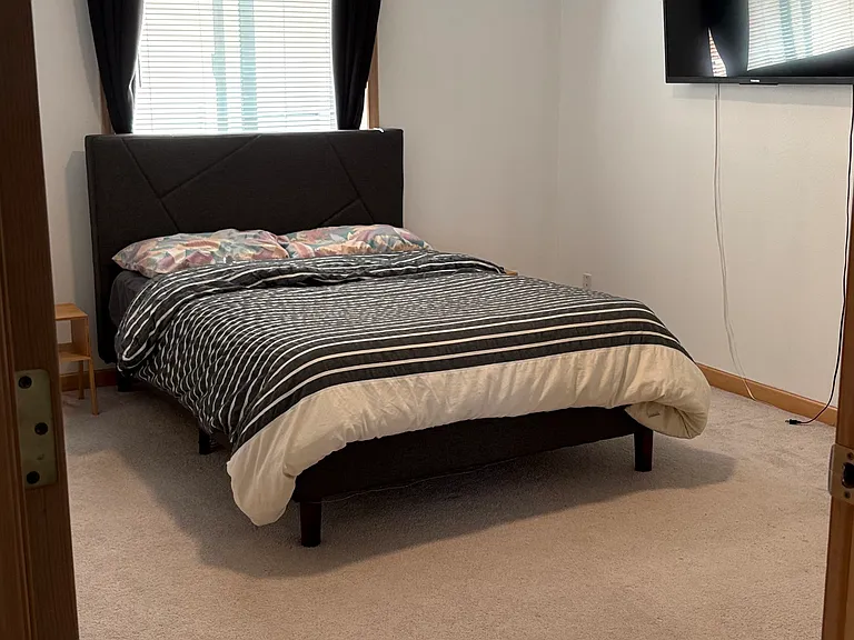 Primary bedroom with a queen size bed, and a mounted TV.