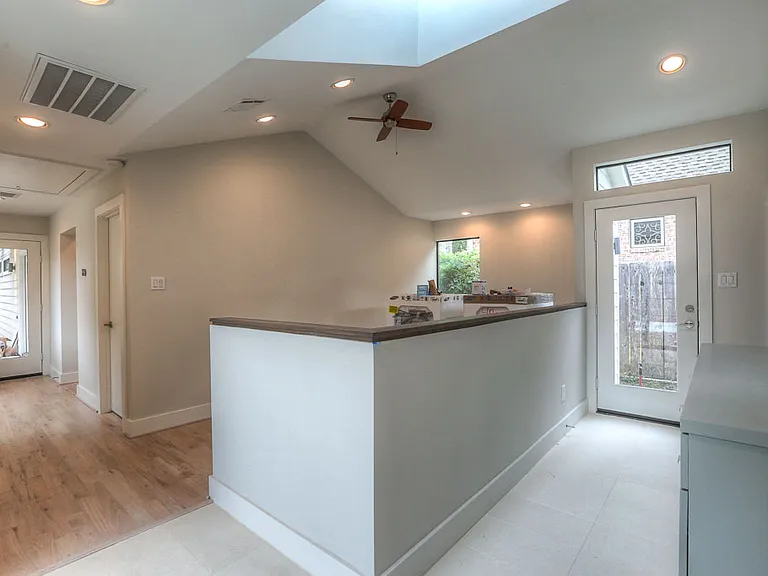 Open hallway with vaulted ceiling and skylight _ looking from the patio doors toward the exercise area, mudroom and rear entry door
