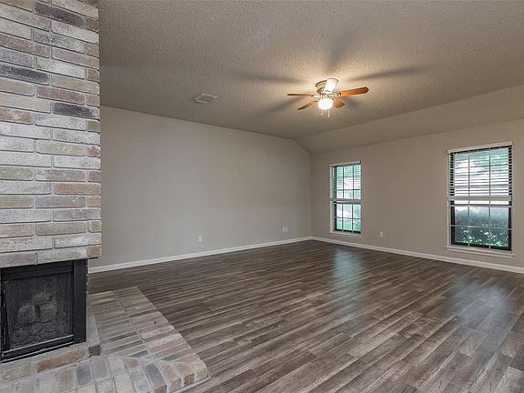 This beautiful living room is complete with a high ceiling complete with a ceiling fan, large windows with privacy blinds, gorgeous hard floors, and a stunning brick fireplace!