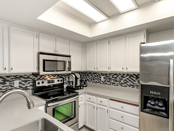 Kitchen has updated shaker cabinets, tile backsplash, quartz counters & stainless appliances.