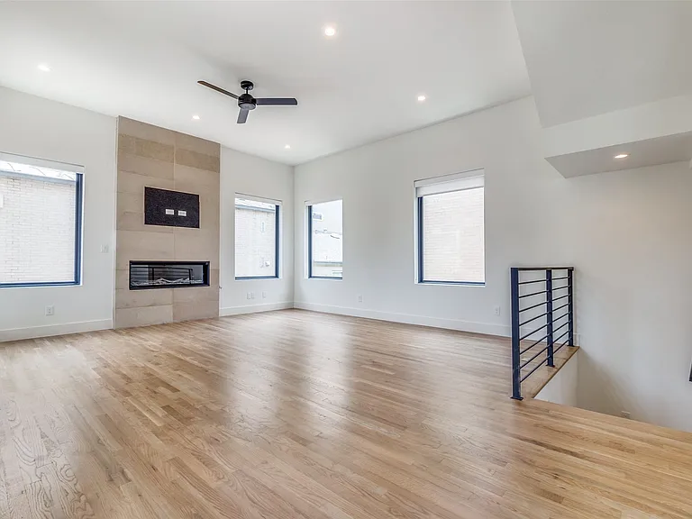 The living area on the second level boasts an abundance of natural light and is anchored by a sleek gas fireplace surrounded by modern stone.