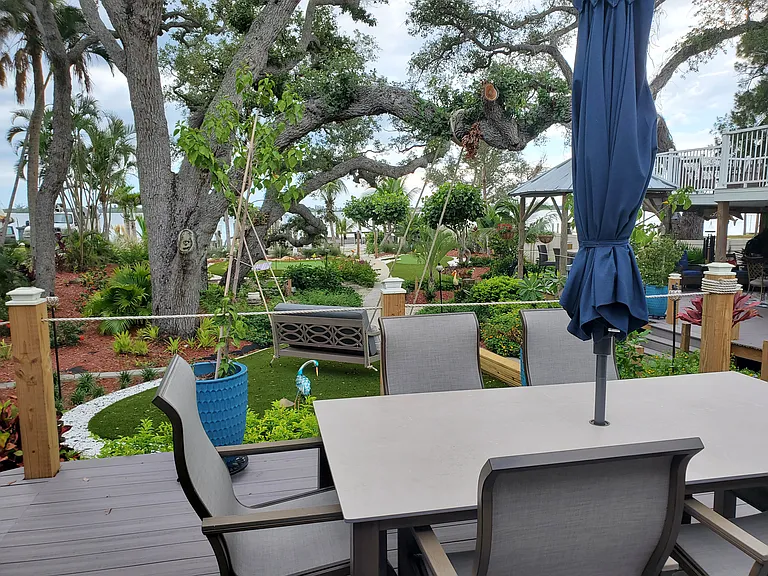 TWO BEDROOM COTTAGE DECKING WITH DINING TABLE, SCREENROOM AND COVERED GLIDER SWING OVERLOOKING THE GARDENS AND BAY