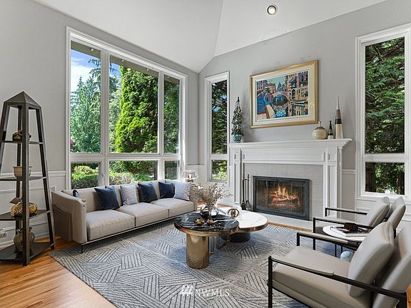 Formal living room with marble surround gas fireplace, tall vaulted ceiling, wainscoting and hardwood floors. (Virtually staged).