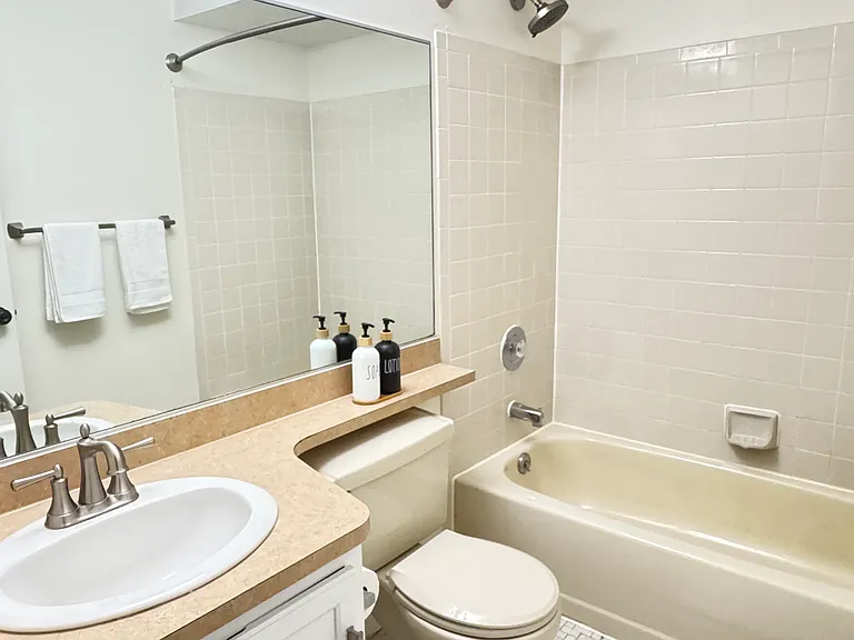 Bright and refreshed guest bathroom has all new brushed nickel hardware and showerheads