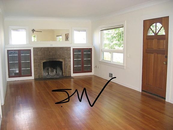 Front Living Room with fireplace and glass door cabinetry and hardwood floors.
