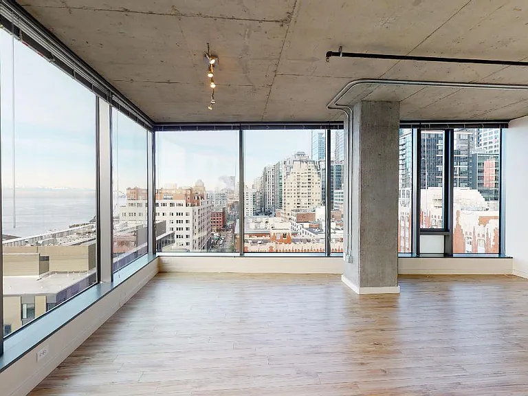Apartment living room with wood-style flooring and floor-to-ceiling windows.