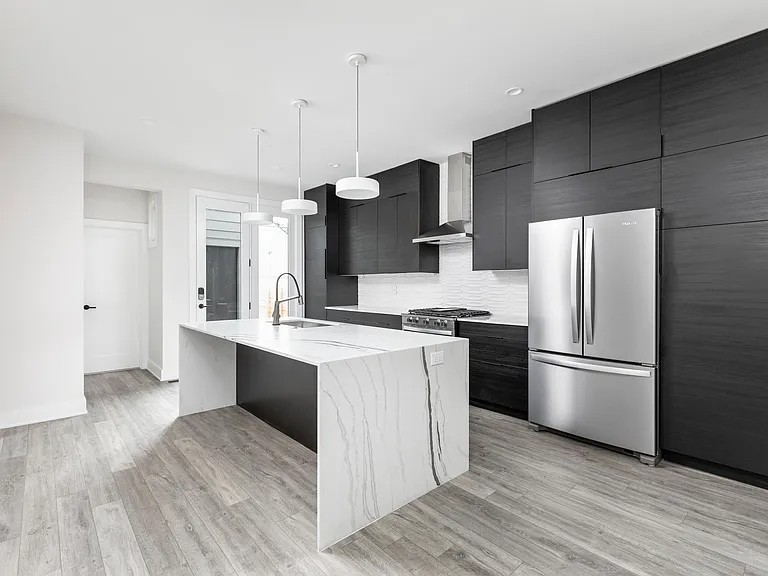 Spacious kitchen with cabinetry to ceiling, waterfall island, stainless steel appliances