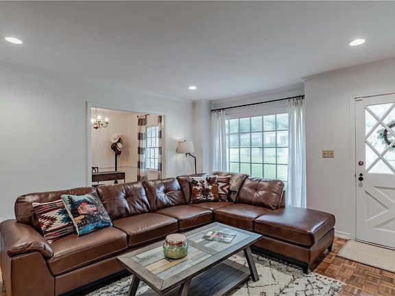 Living room with crown molding, an inviting chandelier, and parquet flooring