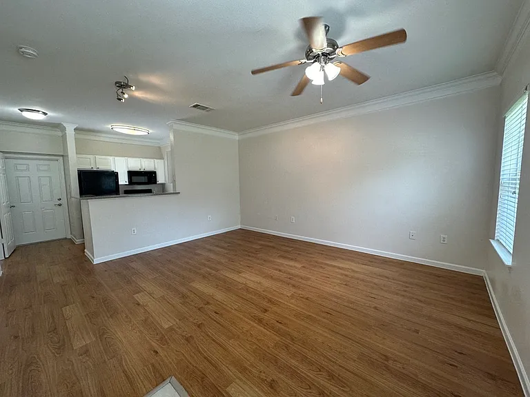 Inviting living space with wood-style flooring, ceiling fan, and open kitchen area. Inviting living space with wood-style flooring, ceiling fan, and open kitchen area.