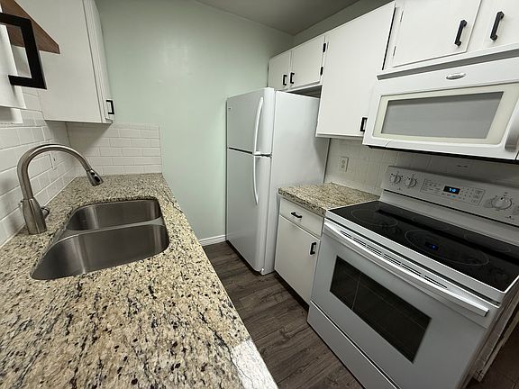 Kitchen with quartz countertops, electric stove, dishwasher, refrigerator and microwave