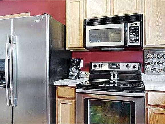 Alternate view of kitchen and side by side refrigerator.