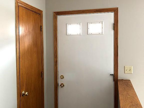 Wood entry in foyer with large coat closet and stylish light fixture.