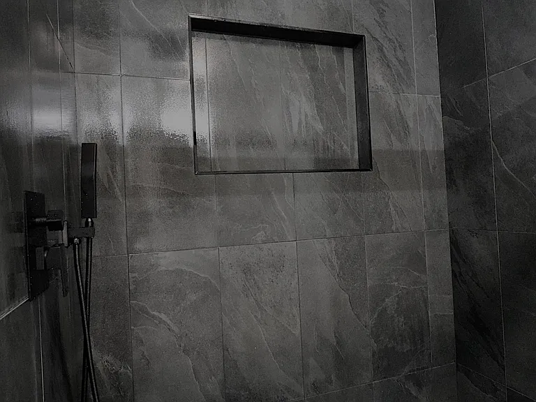 Modern walk-in shower with large-format tile, rain shower head, and built-in niche for storage. Spa-like design.