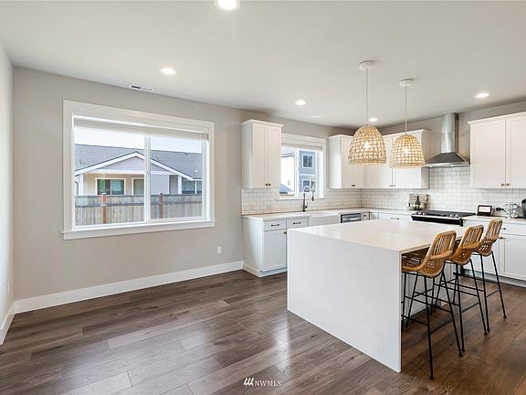 The large kitchen has a quartz waterfall island, farmhouse sink, stainless appliances and gold accents.