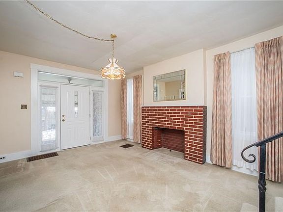 Spacious living room features large windows and brick fireplace.