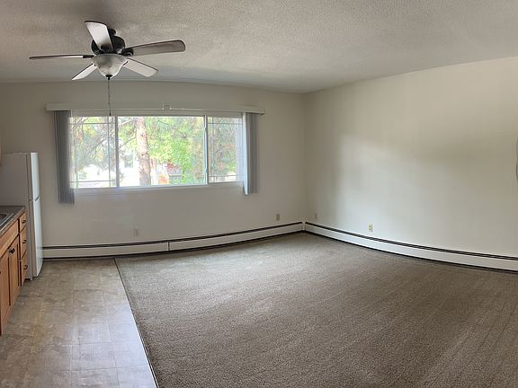 The living room is spacious, with an oversized window, ceiling fan, and air conditioning.