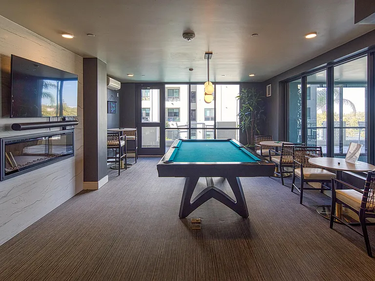 Stylish game lounge with a pool table, fireplace accent wall, and seating arranged for easy indoor entertainment.