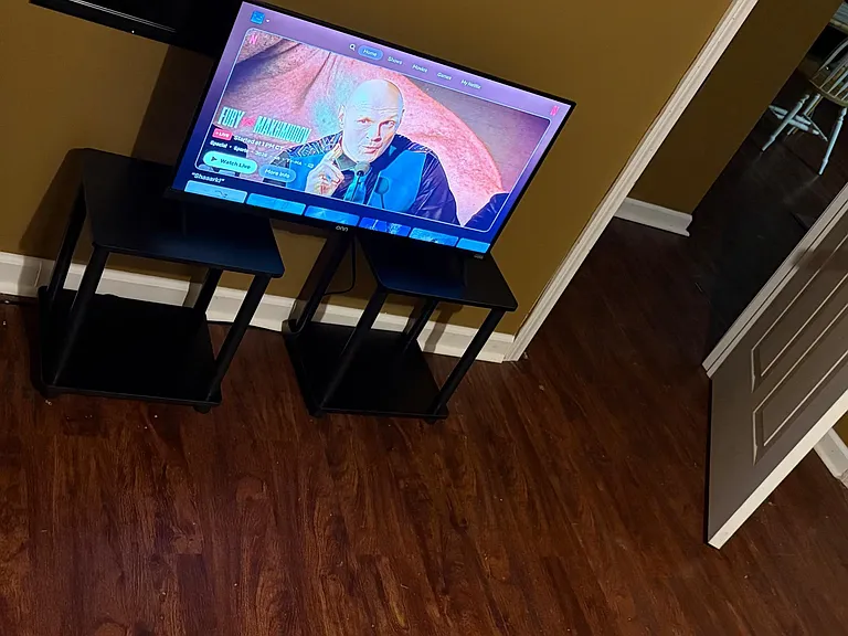 Furnished bedroom featuring wood-style flooring, a bed with comforter, and a TV setup for relaxing after work.