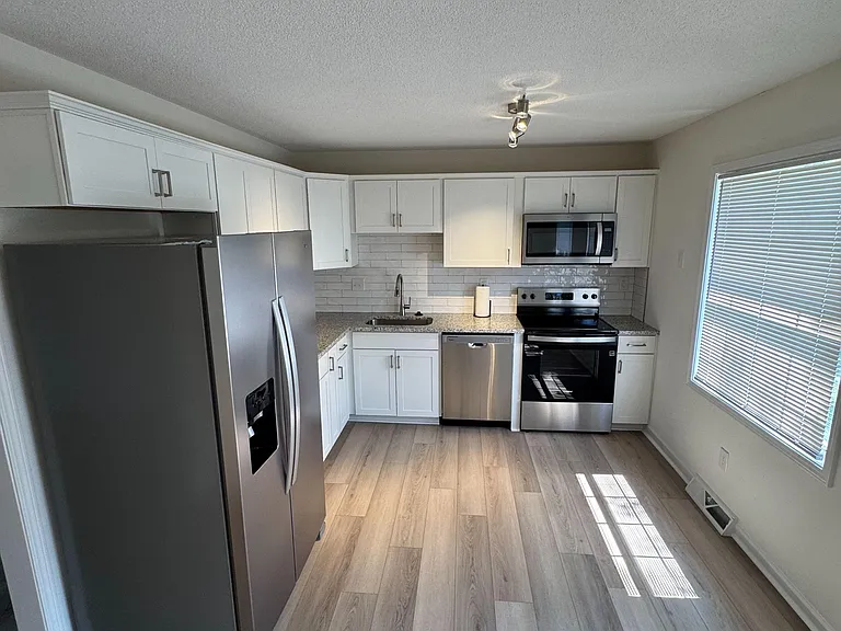 Updated kitchen with shaker cabinetry, tile backsplash, and stainless steel appliances plus ample counter space and storage.