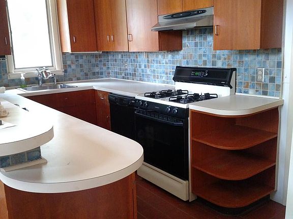 Bright kitchen has cherry cabinets, tile backsplash, breakfast bar, and quarry tile flooring.