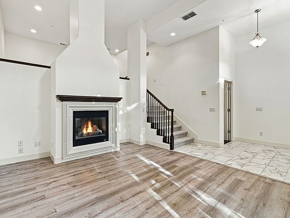 Bright main living room with high ceilings, gas fireplace, and updated flooring.