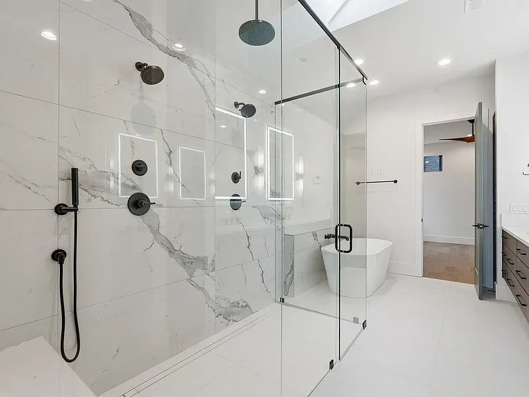 Spa-like primary bathroom with glass enclosed shower, soaking tub, and dual vanity.