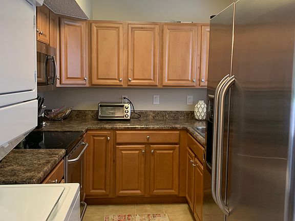 Kitchen with tile floors including stainless steel appliances and stack washer/dryer