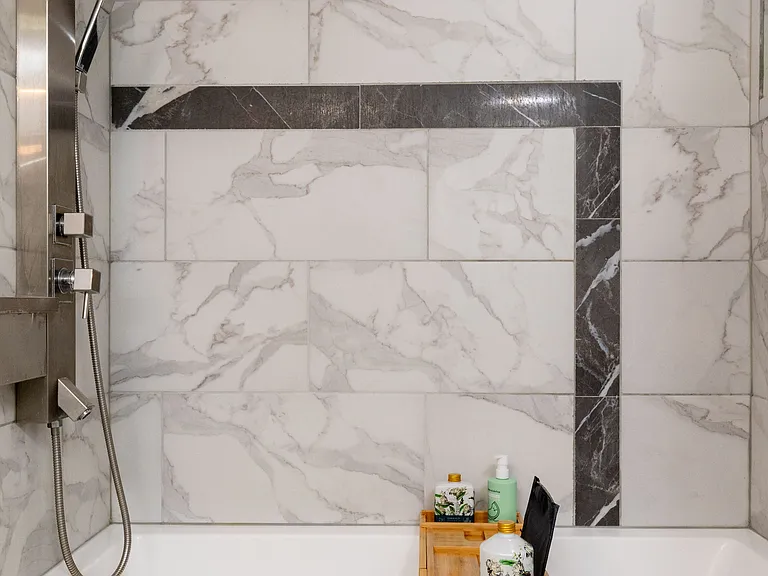 This refreshed bathroom features a sleek vanity with soft lighting and a relaxing shower-tub combo with marble-style tile. Thoughtfully stocked with essentials for a comfortable and easy stay.