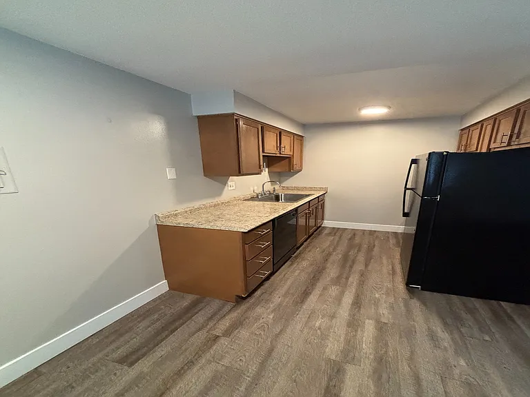 Modern kitchen with sleek granite countertops, elegant wood cabinetry, and contemporary flooring, perfect for stylish living.