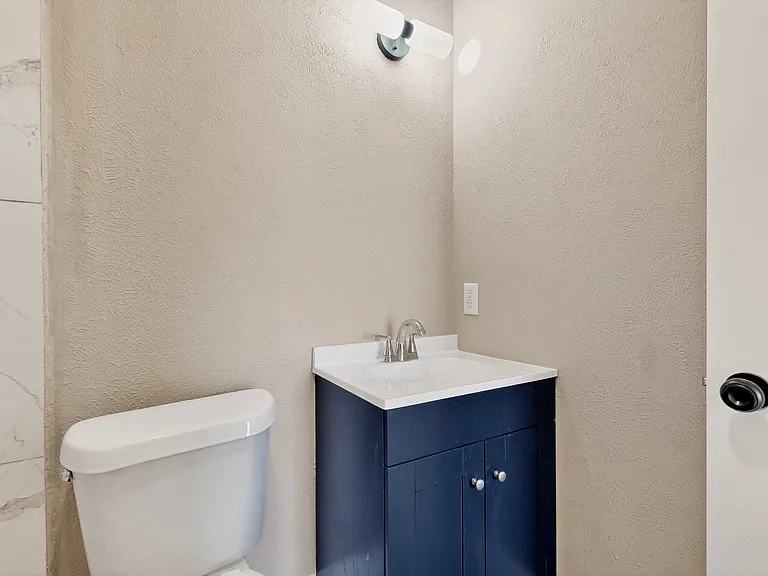 Half bath with vanity and a textured wall