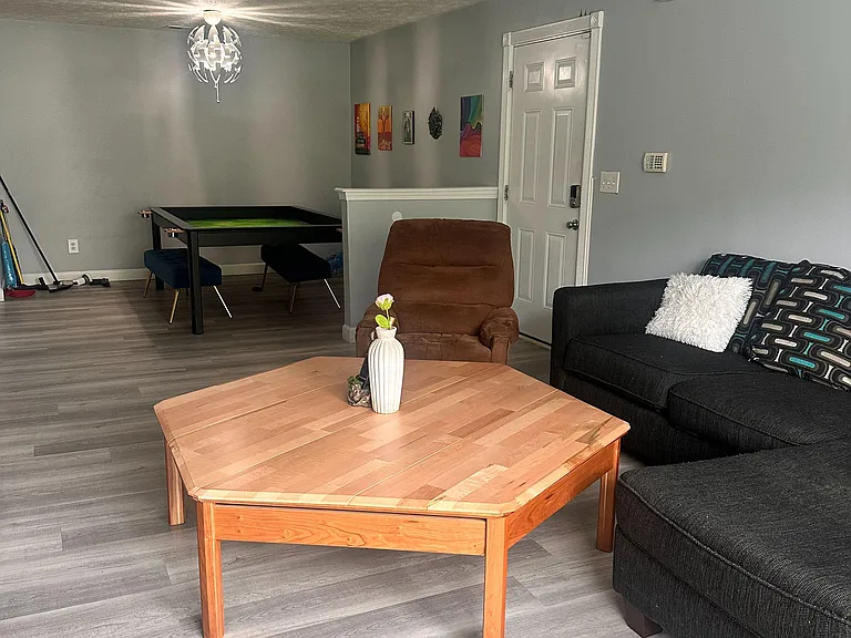 Spacious shared living area with comfortable seating, coffee table, and a game tableideal for relaxing or socializing.