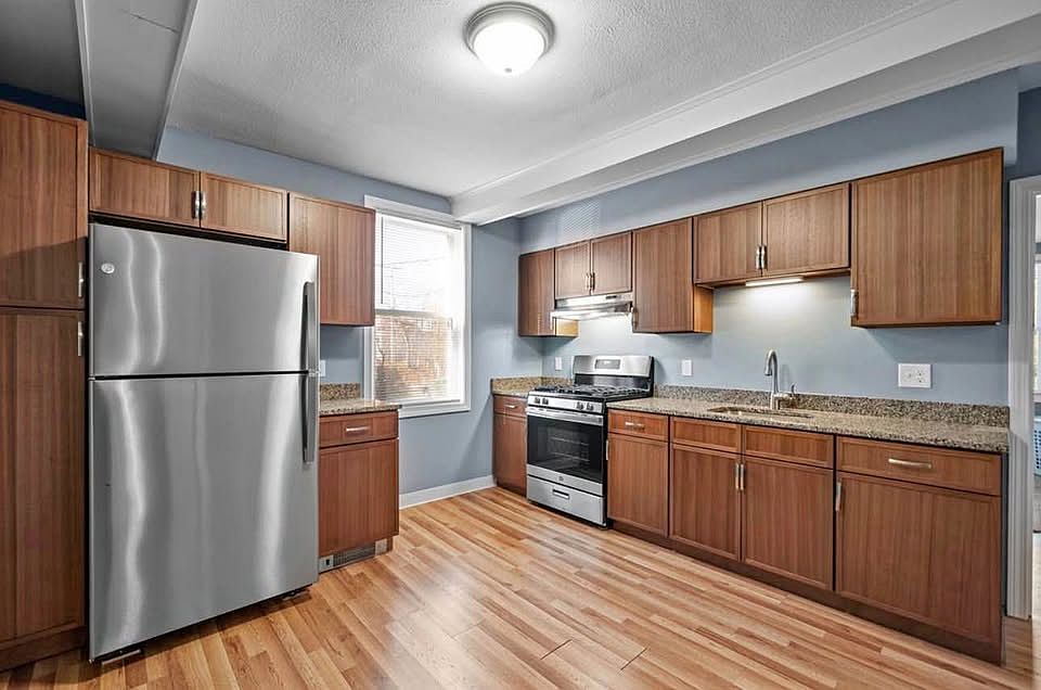 The heart of this home is a stunning kitchen featuring granite countertops, custom grey shaker cabinetry, and a full suite of stainless steel appliances (including a dishwasher and built-in microwave). The classic white subway tile backsplash adds a high-