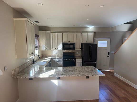 Kitchen with refrigerator, stove/oven, microwave, and dishwasher. Window over sink looks out to patio area.